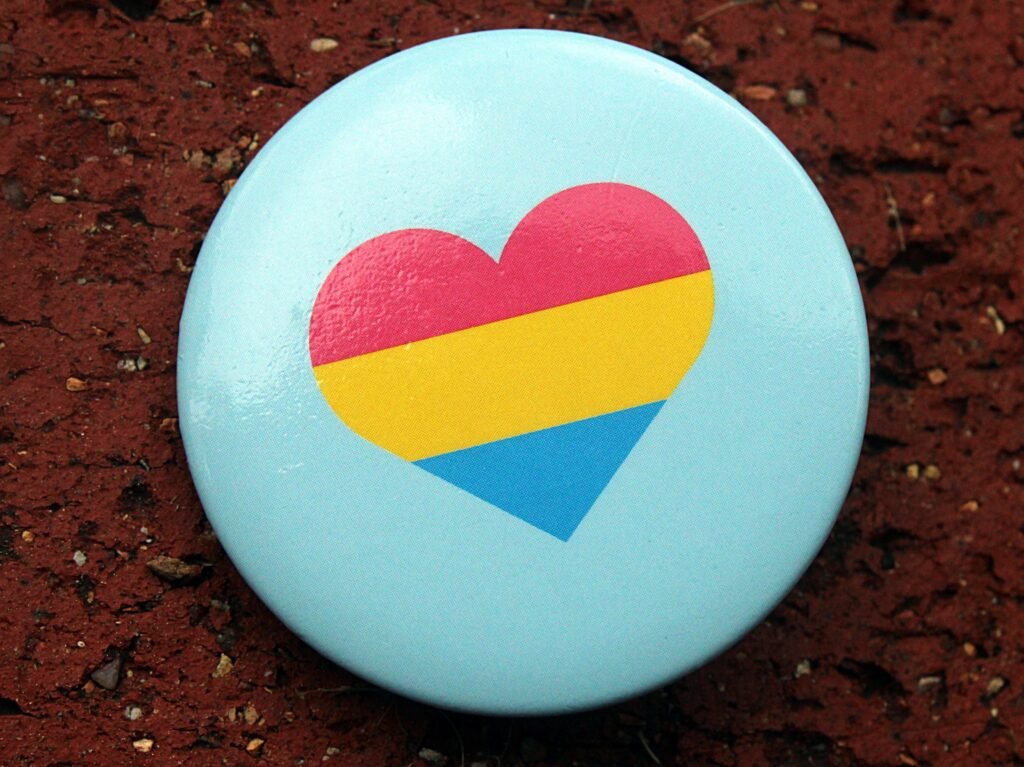A button with the pan flag in a heart on a blue background. Photo by merripat on Flickr (June 2023).